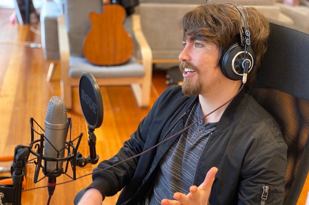 Daniel Muñoz with headphones on, speaking to a podcasting microphone